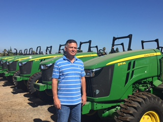 John Gilligan standing in front of tractors