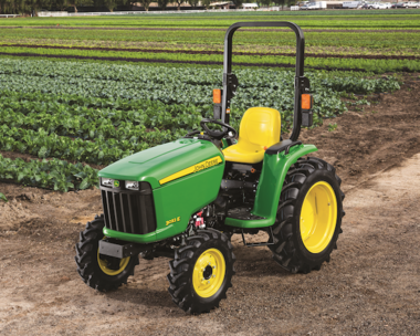 A John Deere 3032E Compact Tractor sitting out in a field of crops